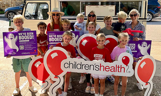 Group of kids and adults holding up Children's Health Booed signs.